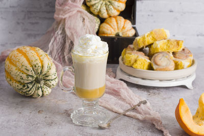 Pumpkin cinnabons and latte for dessert, holiday table with pastries, home sweet