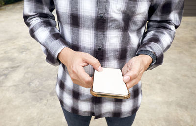 Midsection of man holding mobile phone