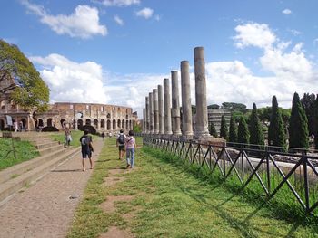 Rear view of people walking in park against sky