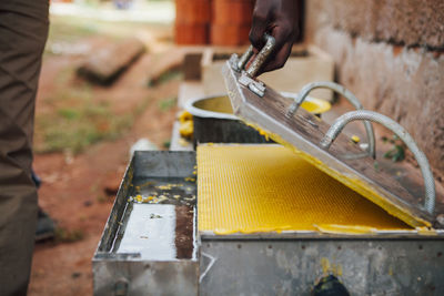 Cropped image of person opening metal container with wax on field