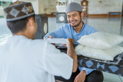 Smiling man receiving envelope in mosque