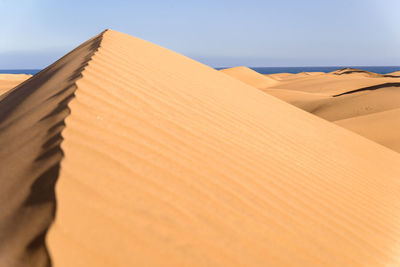 Sand dunes in desert against clear sky