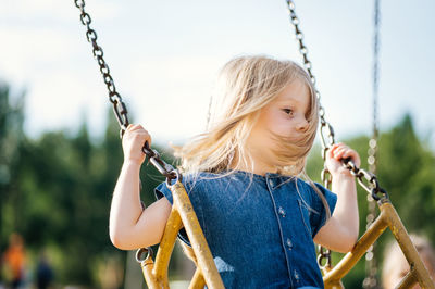 Close-up of girl holding swing in playground