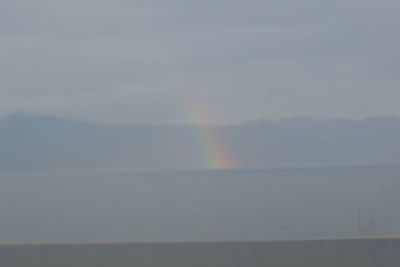Scenic view of rainbow over sea against sky
