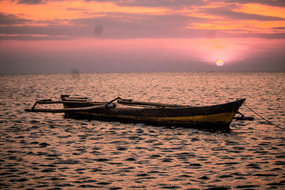 Boat in sea against sky during sunset