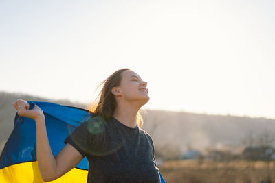 Woman holding a yellow and blue flag of ukraine in outdoors