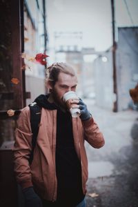 Young man holding ice cream standing in city