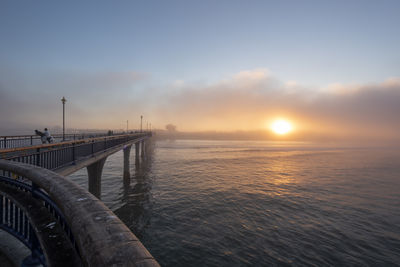 Bridge over sea against sky during sunset