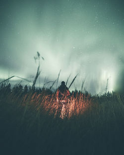 Low angle view of silhouette man standing on grassy land against sky at dusk