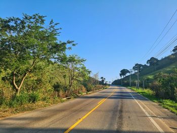 Road amidst trees against clear sky