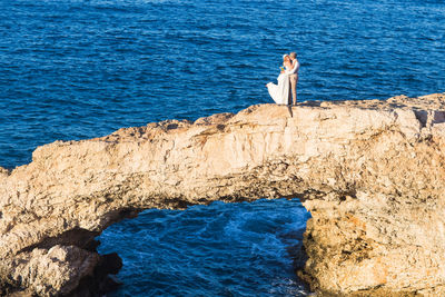 Woman standing on rock by sea