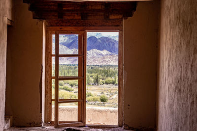 Trees and building seen through open window of abandoned house