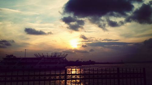 Silhouette of built structure against cloudy sky at sunset