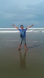 Rear view of woman standing at beach against sky