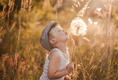 Beautiful young woman with dandelion on sunny day
