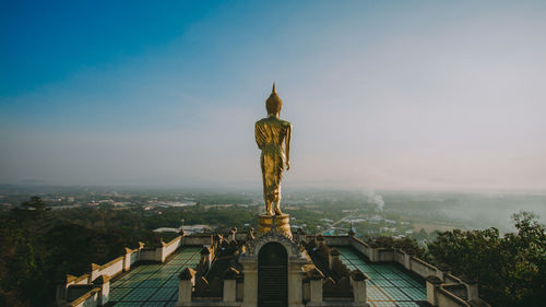 Statue on building against landscape