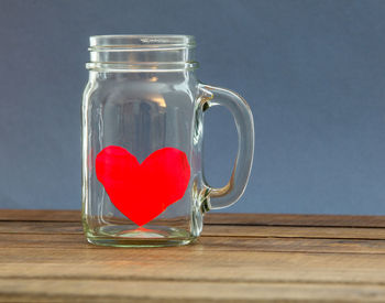 Close-up of heart shape on glass mason jar against wall