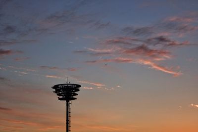 Low angle view of communications tower against dramatic sky