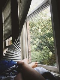 Low section of woman sitting by window at home