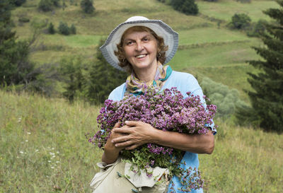 Portrait of a smiling young woman with oregano herbs flowers in her hands, beautiful nature