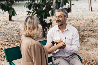 Couple holding hands while sitting at bench