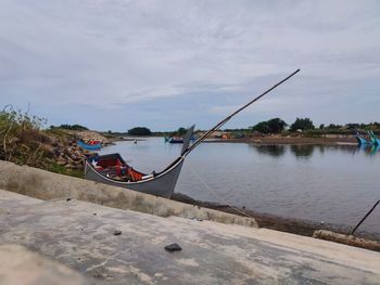 Fishing boat moored in sea against sky