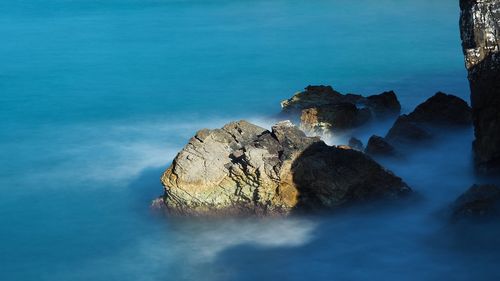 Rock formation on sea against blue sky