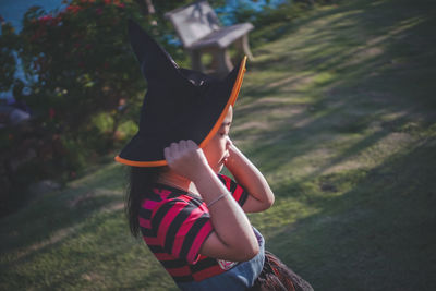 Side view of girl wearing witch hat on field