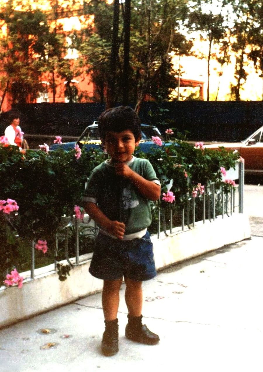 plant, one person, full length, tree, standing, nature, front view, child, looking at camera, childhood, portrait, men, casual clothing, flower, smiling, day, happiness, leisure activity, lifestyles, outdoors, growth, emotion, christmas tree, spring, architecture, toddler, flowering plant, person, footpath, innocence, female, sunlight, clothing