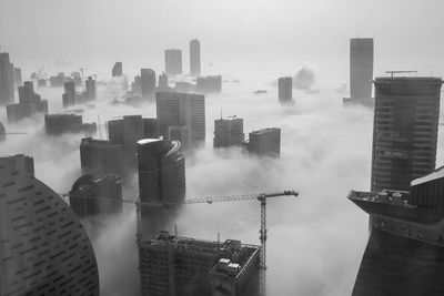 Smoke emitting from buildings against sky in city