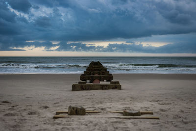 Lifeguard hut on beach against cloudy sky