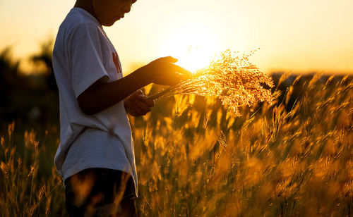 Midsection of man standing on land against sky during sunset