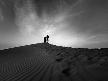 Rear view of people at desert against sky