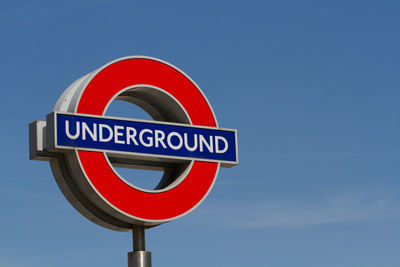 Low angle view of sign board against blue sky