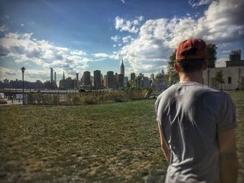 Rear view of man looking at cityscape against sky