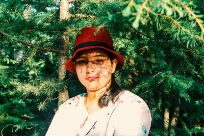 Portrait of young woman standing against trees