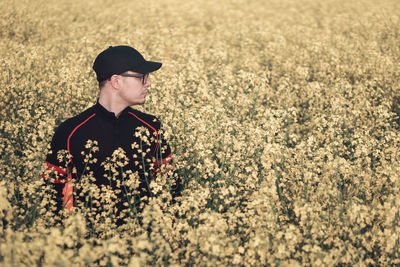 Young man standing amidst plants on field