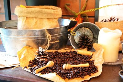 Close-up of coffee beans by burlap and candle on table