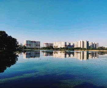 Buildings by lake against blue sky