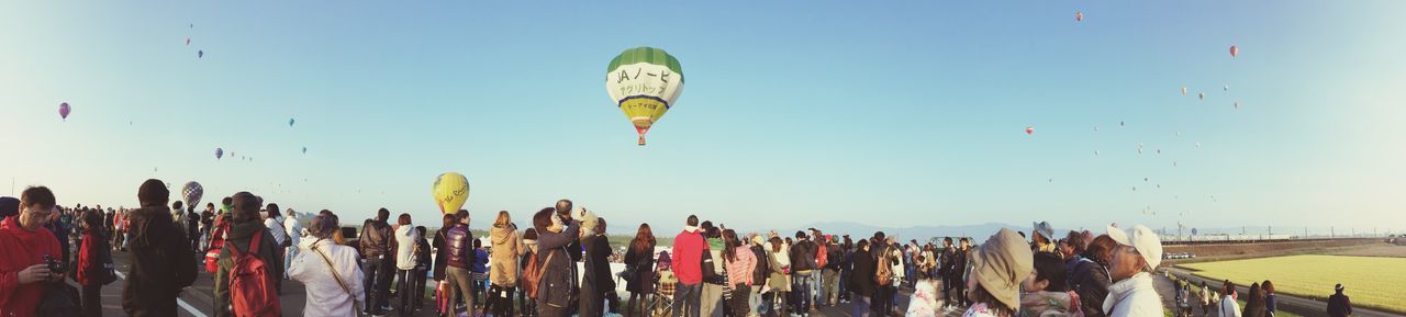 flying, clear sky, multi colored, mid-air, copy space, flag, large group of people, in a row, sky, beach, day, leisure activity, outdoors, bird, hot air balloon, blue, low angle view, freedom, variation