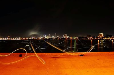 Illuminated light trails in city against sky at night