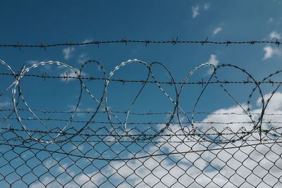 Barbed wire fence against blue sky