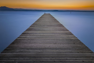 Pier over sea against sky during sunset