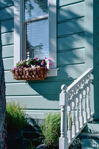 Vintage wooden house with ornate railing along steps and flowers in window box