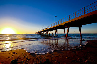 Bridge over sea against clear sky at sunset