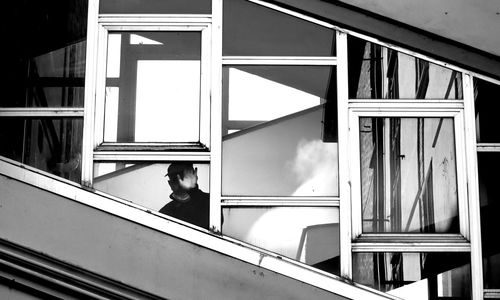 Side view of man standing by railing against building