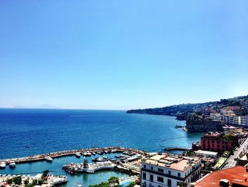 Scenic view of blue sea by buildings against clear sky on sunny day