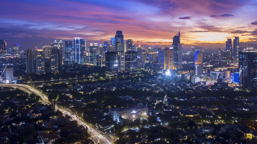 Aerial view of city lit up against cloudy sky