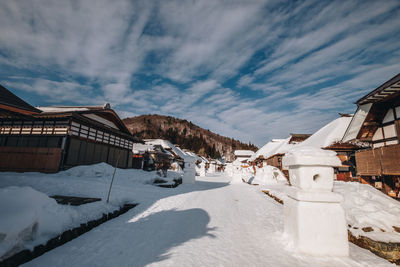 Snow covered houses by buildings against sky