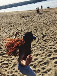 Rear view of girl with dog on beach